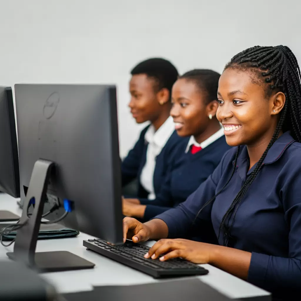Three students focused on computer screens, showcasing engagement in a learning environment with modern technology.